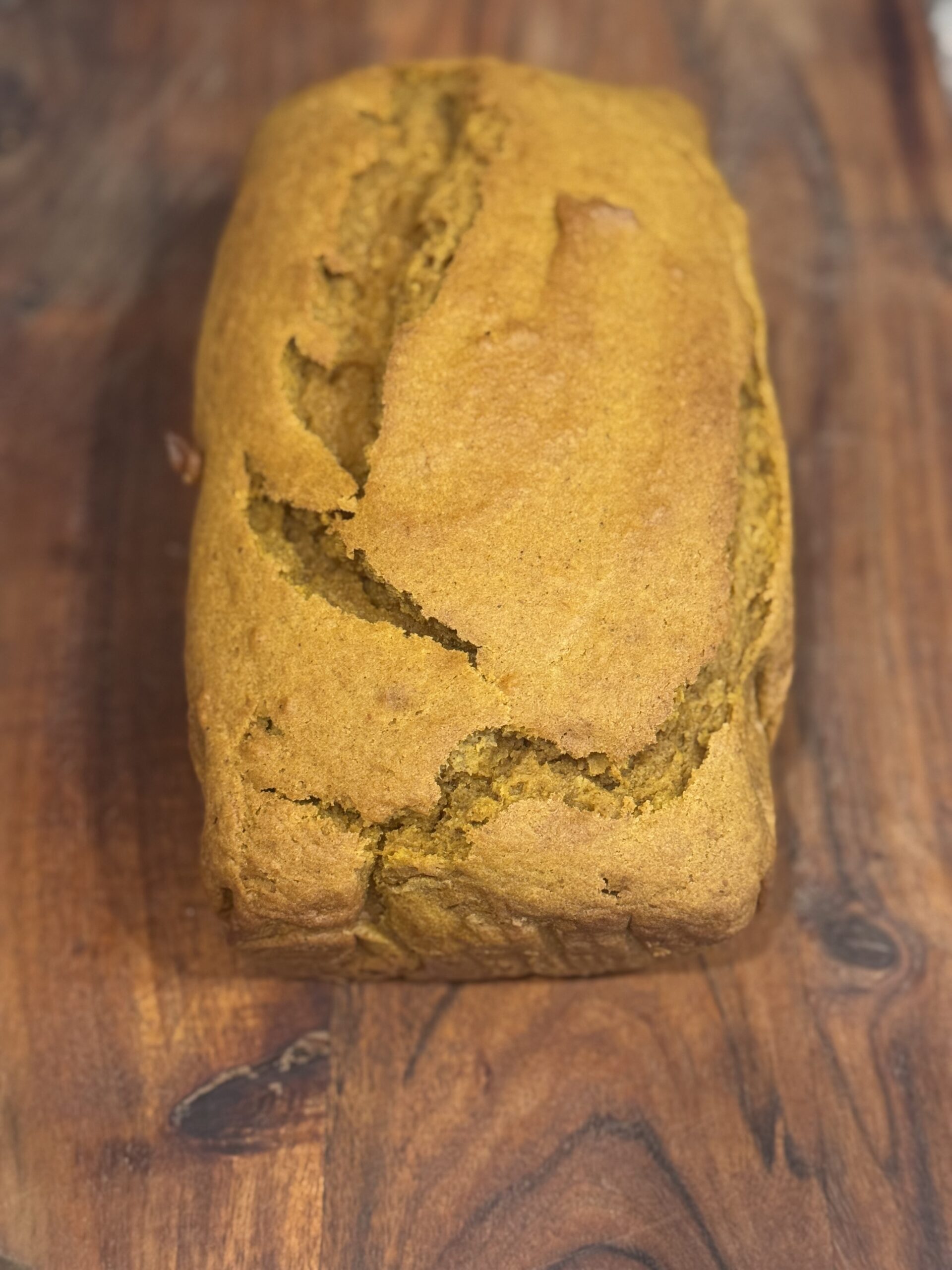 Freshly baked loaf of dairy-free pumpkin bread on parchment paper.